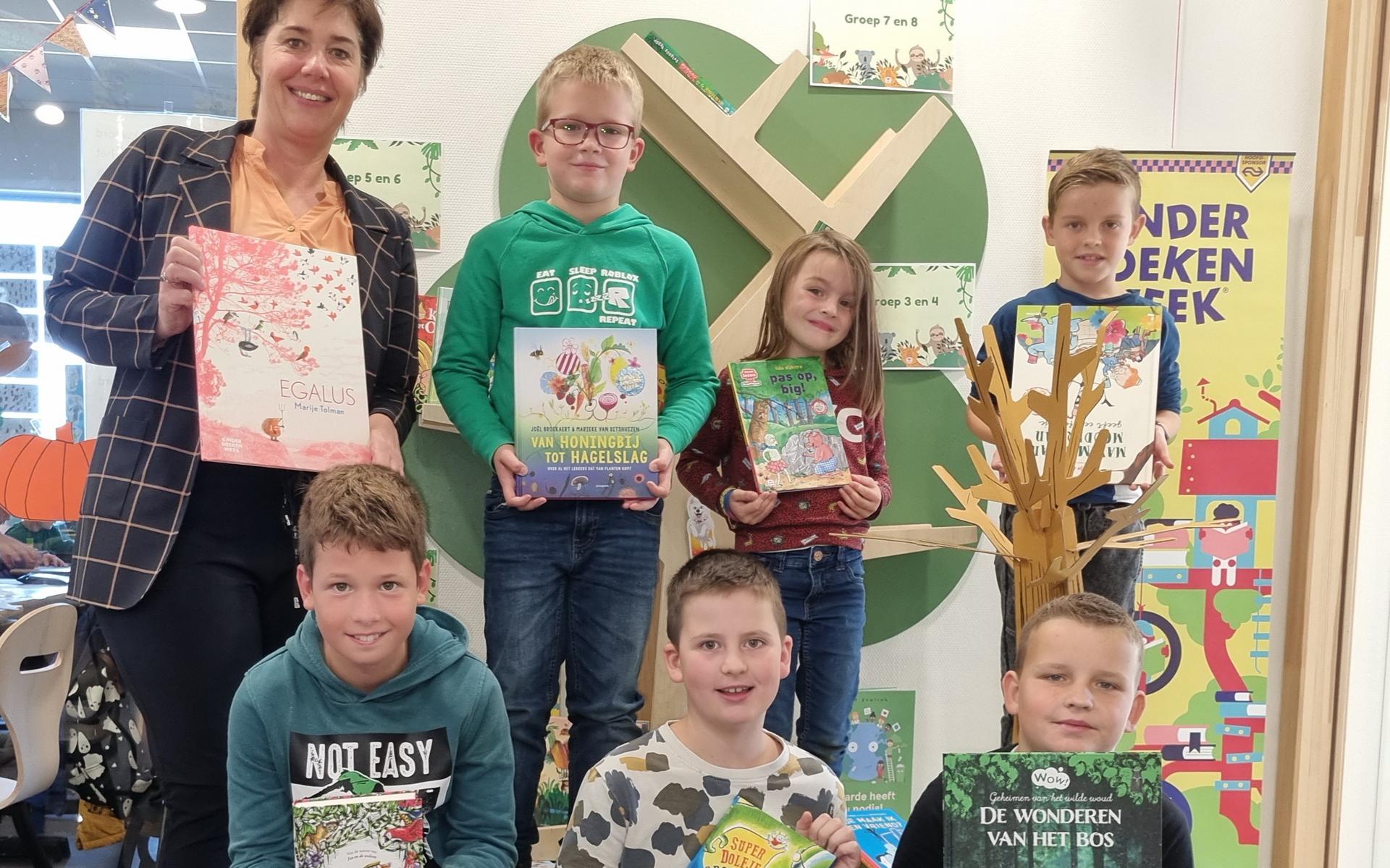 De leerlingenraad van basisschool 't PuzzelsTuk showt een aantal nieuwe boeken van de schoolbibliotheek. Links directrice Jacqueline Driezen.