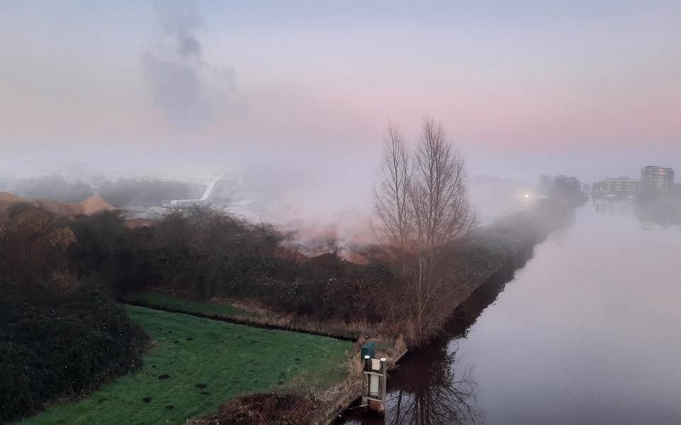 Broei van houtsnippers zorgt voor een mistlaag. Boven deze laag is de rook uit de schoorstenen van de centrale te zien.
