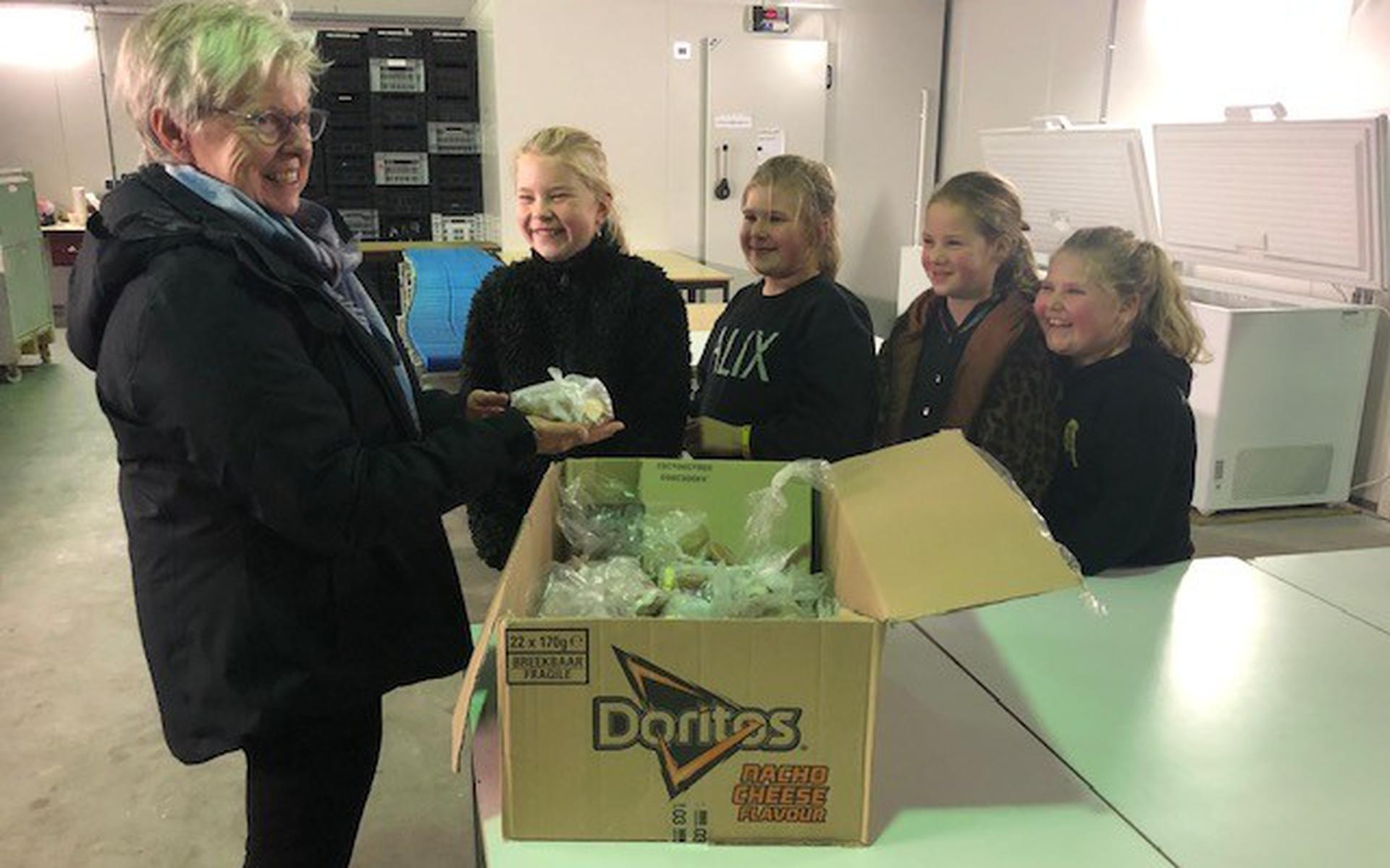 De trotse vriendinnen overhandigen de doos met snoep aan de Voedselbank.