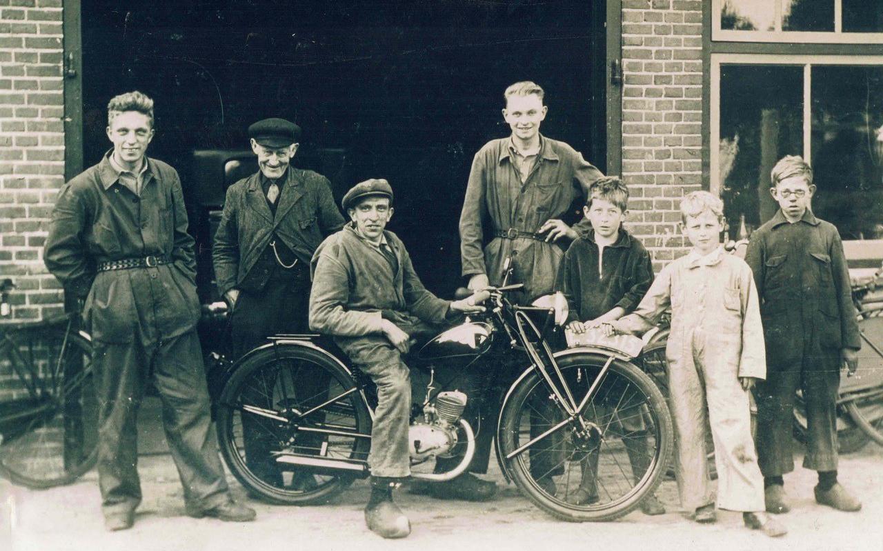 Op deze foto uit 1924, twee jaar na de oprichting, poseert Pé Vredenburg met personeel en een prachtige motorfiets voor zijn bedrijf.