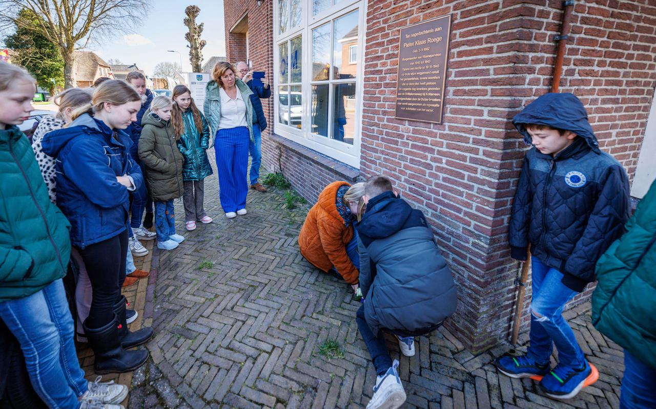 Leerlingen van De Lisdodde leggen een krans bij de gedenkplaat voor de in de Tweede Wereldoorlog doodgeschoten burgemeester Roege.