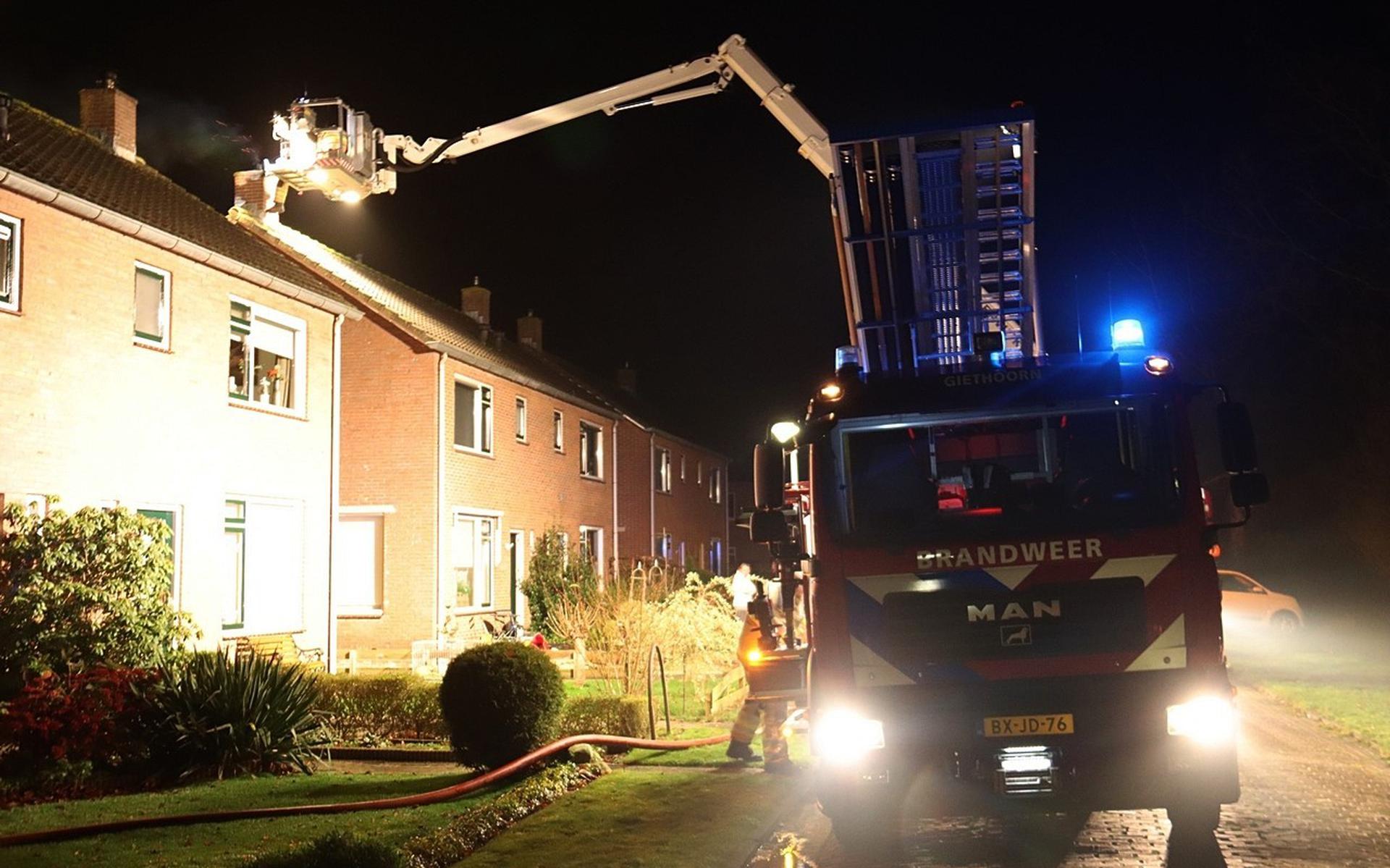 Met een hoogwerker kan de brandweer bij de schoorsteenbrand aan de Sportlaan in Giethoorn.