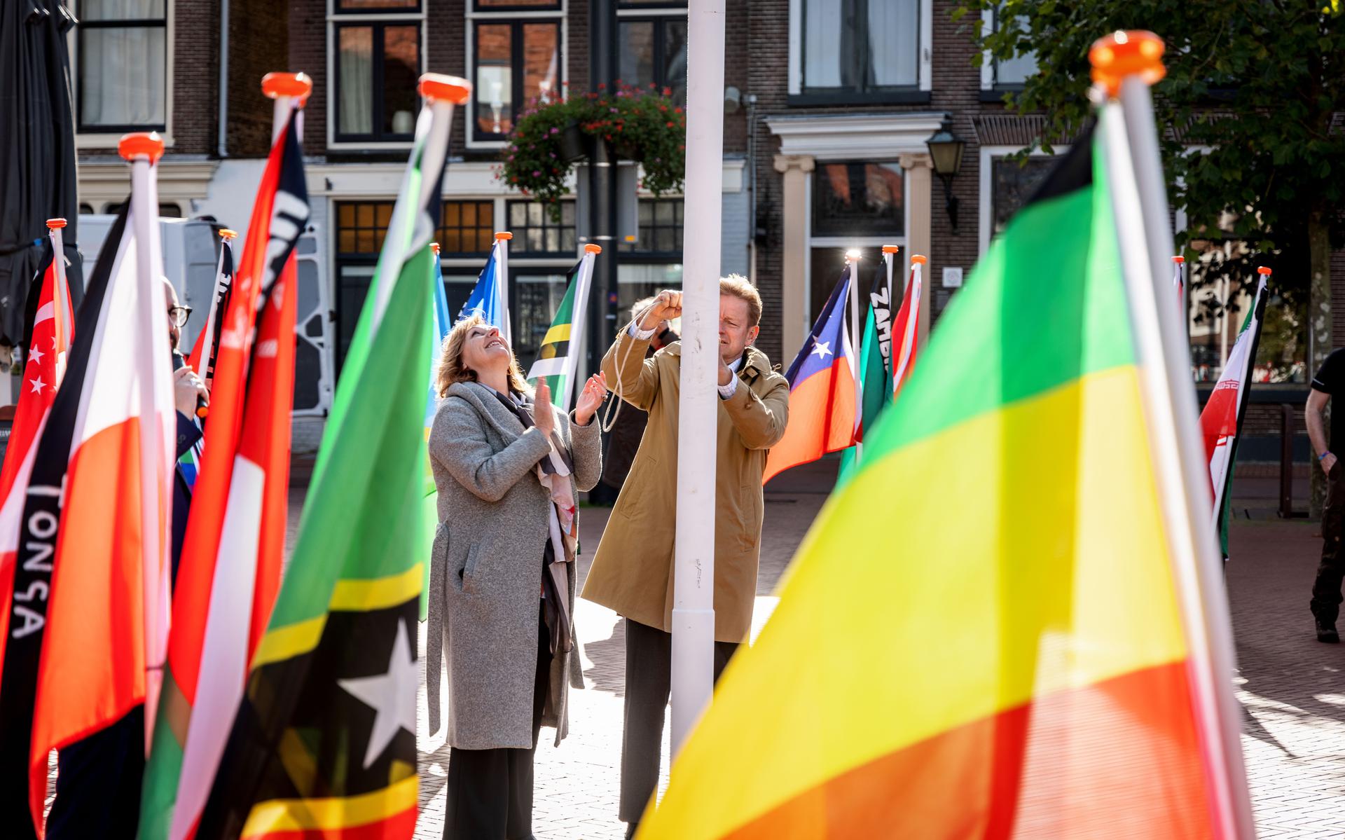 Burgemeester Rob Bats en wethouder Trijn Jongman hesen de regenboogvlag op de Markt.