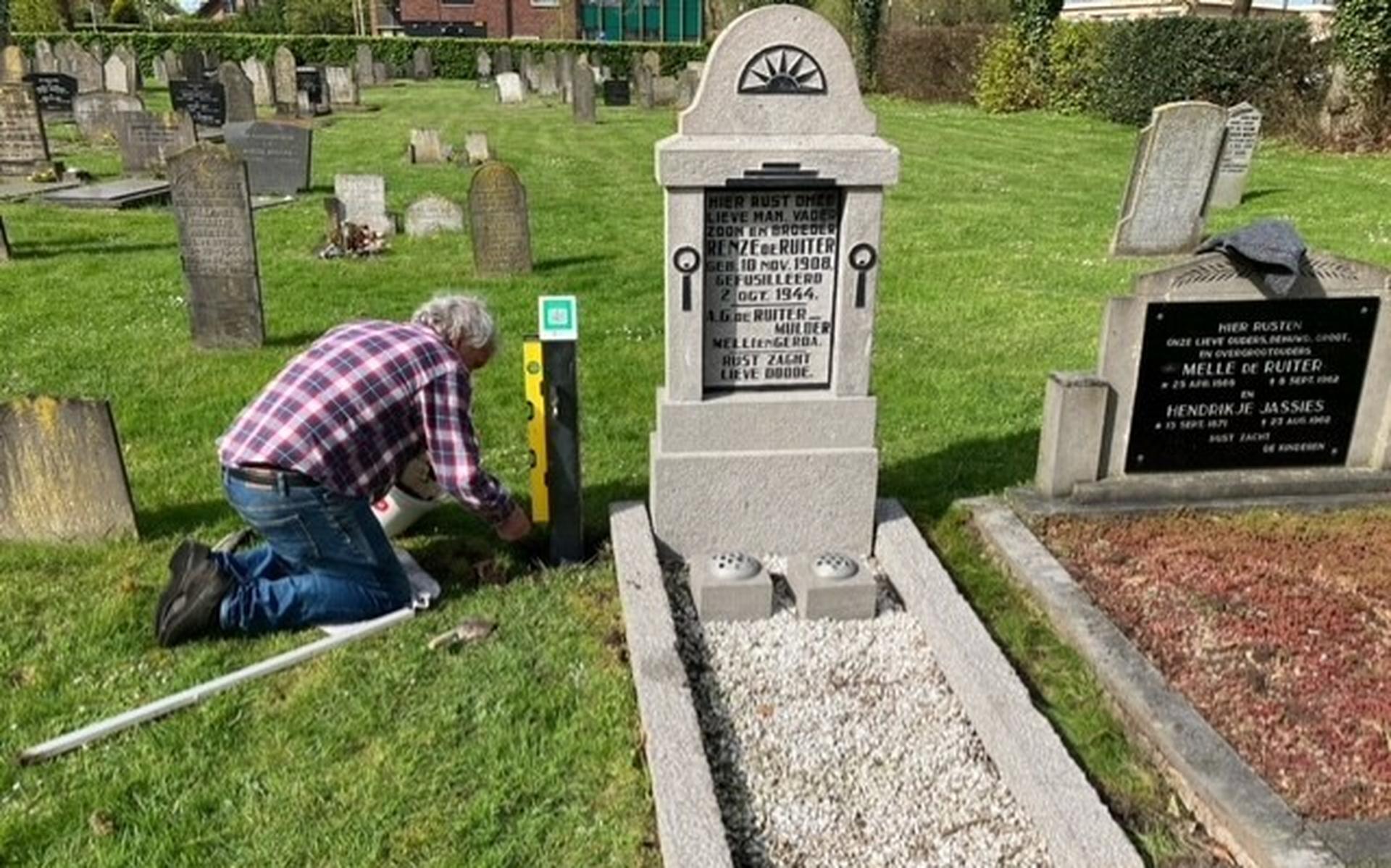 Bennie Froklage plaatst het paaltje met de QR-code bij het graf van Renze de Ruiter.