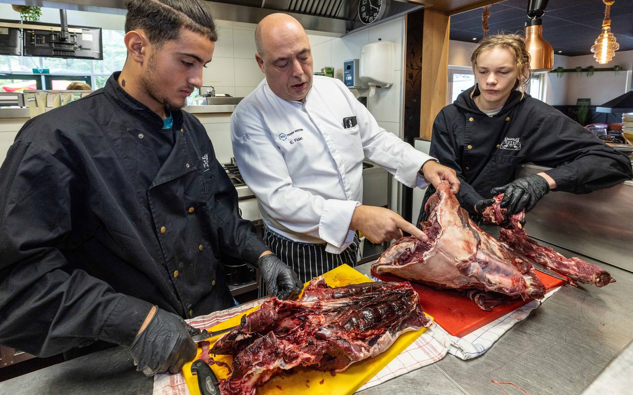 Leerkracht praktijkonderwijs Erdo Fidan laat in de keuken van het restaurant van Residence De Eese aan twee leerlingen van de onderwijspraktijkgroep Horeca zien hoe een hert uit te benen.