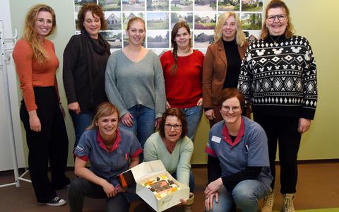 Ria Bijkerk ontvangt de taart uit handen van haar collega's van Thuiszorg De Reune. 