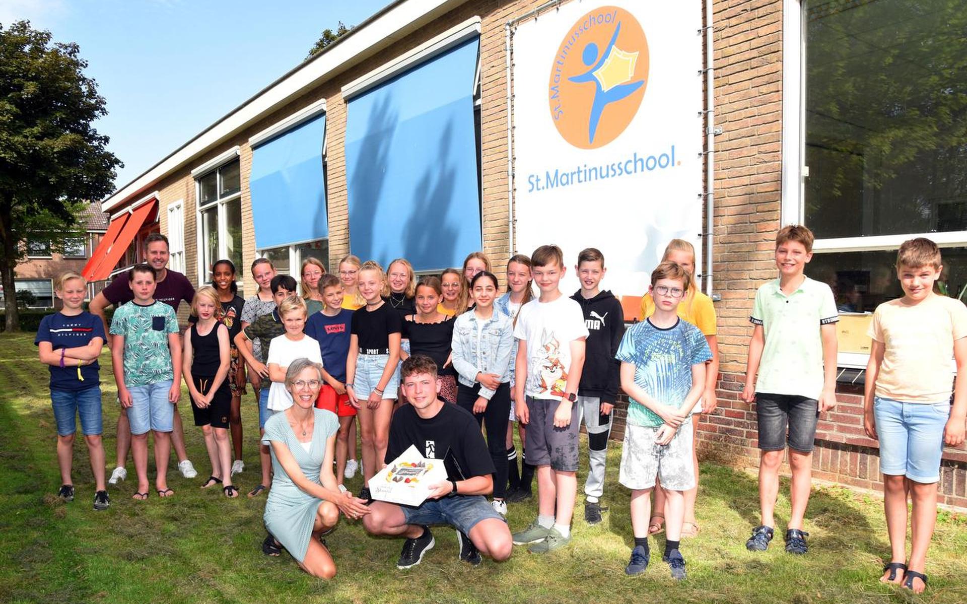 Toby Boonstra met de taart, de leerkrachten en kinderen van de Sint Martinusschool.